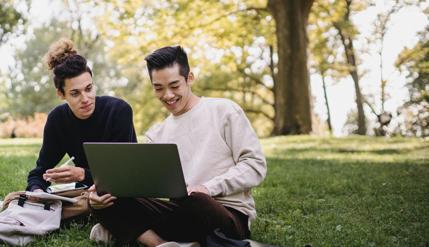 Doane students looking at a laptop and talking on the lawn.